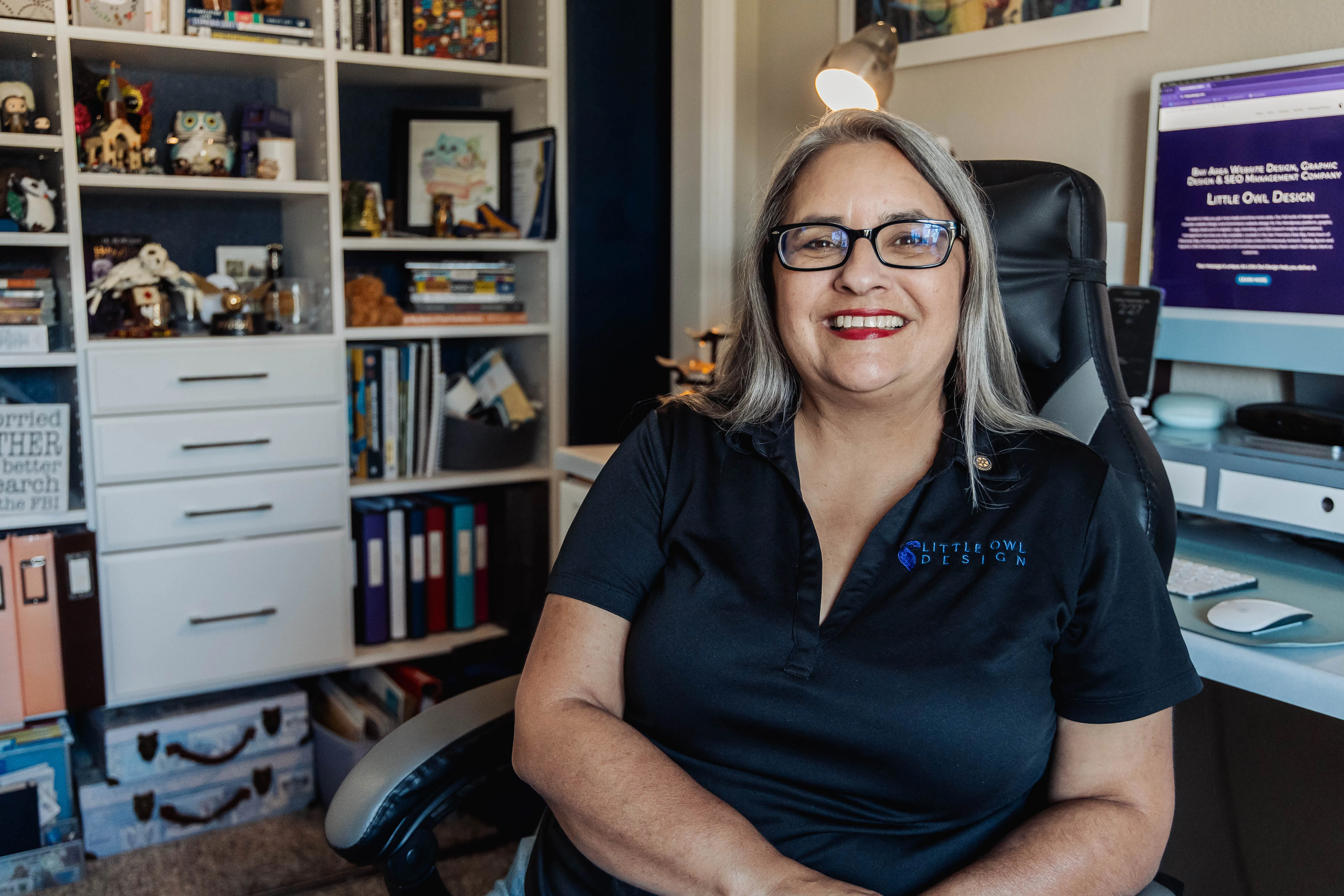 Karri Reiser — founder of Little Owl Design, smiling at her desk